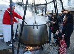 Szakács gőzölgő nagy bográcsban főz a halfesztiválon, körülötte érdeklődők